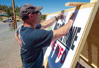 Public Information Officer Alberto Ortega with Fire Prevention and Investigation puts up a Welcome Home poster in the city of Greer, Ariz. on Monday, June 20, 2011. The U.S. Forest Service says residents of Greer are being allowed to return home Monday. Evacuees have to present valid identification verifying residency in order enter. AP Photo 